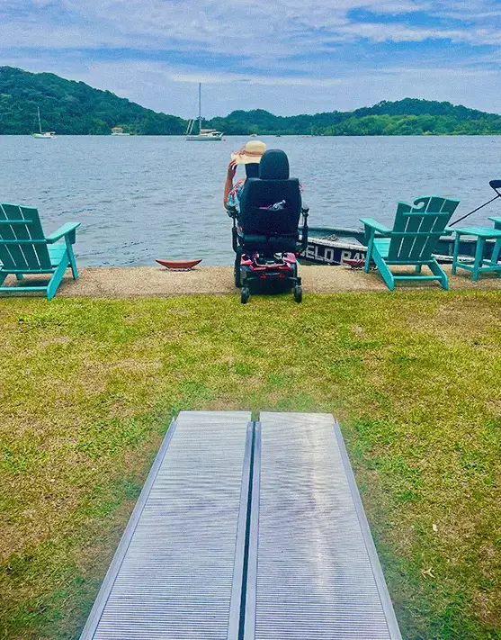 Tourist in a wheelchair, accessible ramp facing the sea